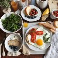 Frühstücksteller mit Spiegelei, Tomaten, Brot und Beilagen