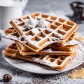 Gestapelte Waffeln mit Puderzucker bestreut auf einem Teller