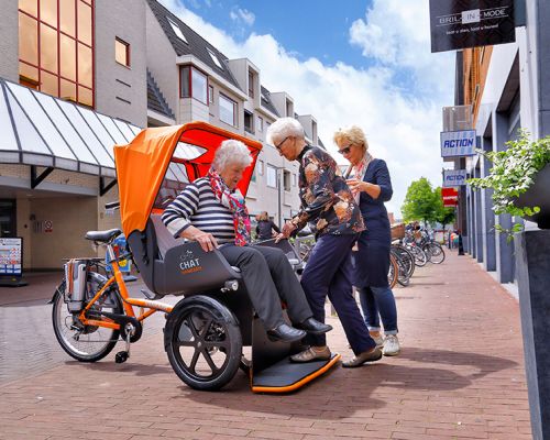 Zwei Seniorinnen besteigen ein Lastenfahrred in einer Fußgängerzone